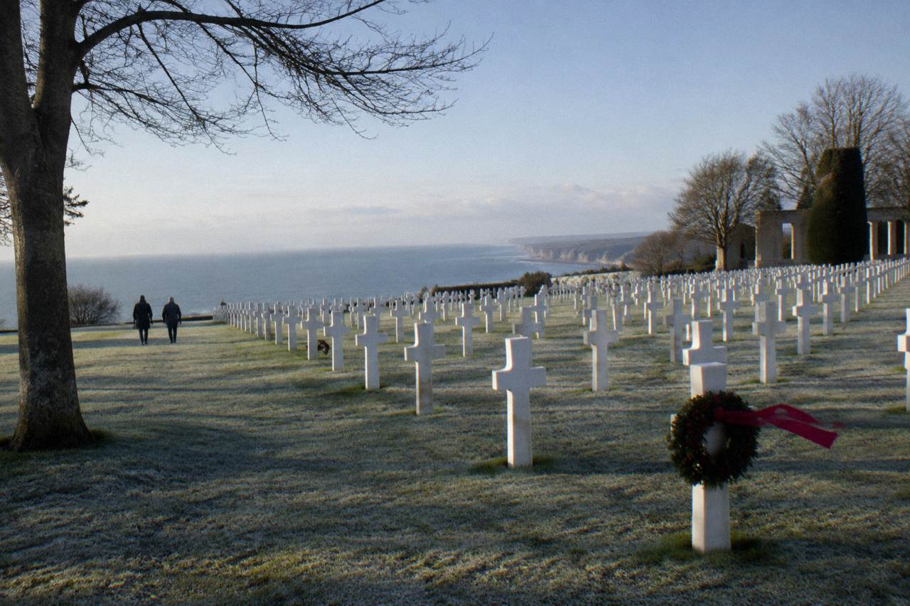 Rows of white marble headstones stretching across the lawn of the Normandy American Cemetery above the sea