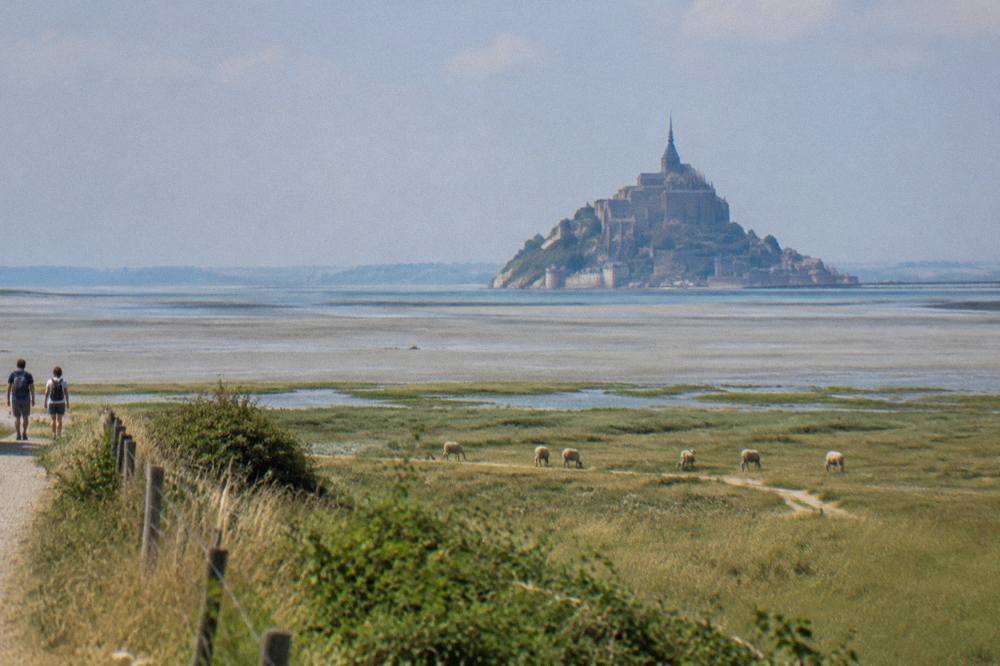 The walled island of Mont-Saint-Michel seen across open sand at low tide