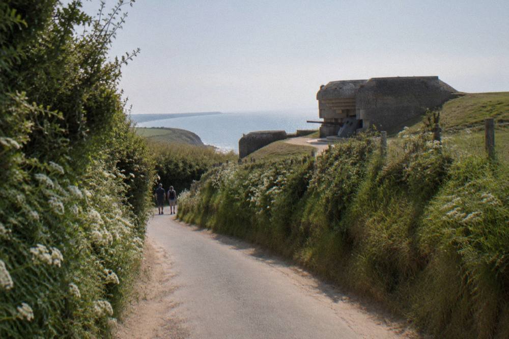 Country road through hedged farmland leading toward the Normandy coast