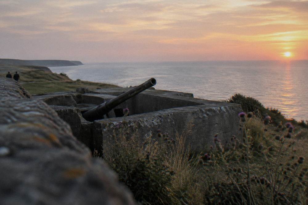 Concrete bunker remains on a clifftop above the sea at dusk