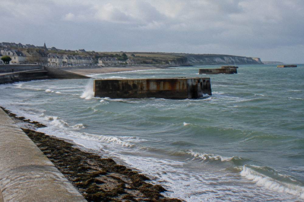 Remains of the artificial harbour breakwater standing in the water off Arromanches