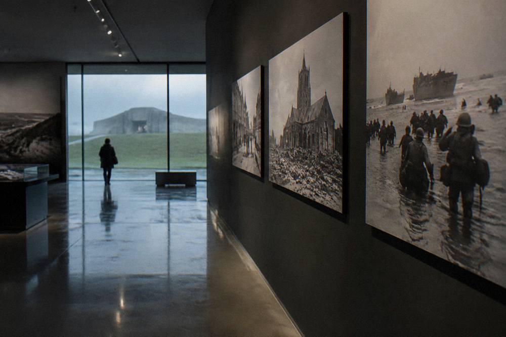 A dimly lit museum gallery with wartime photographs along the walls