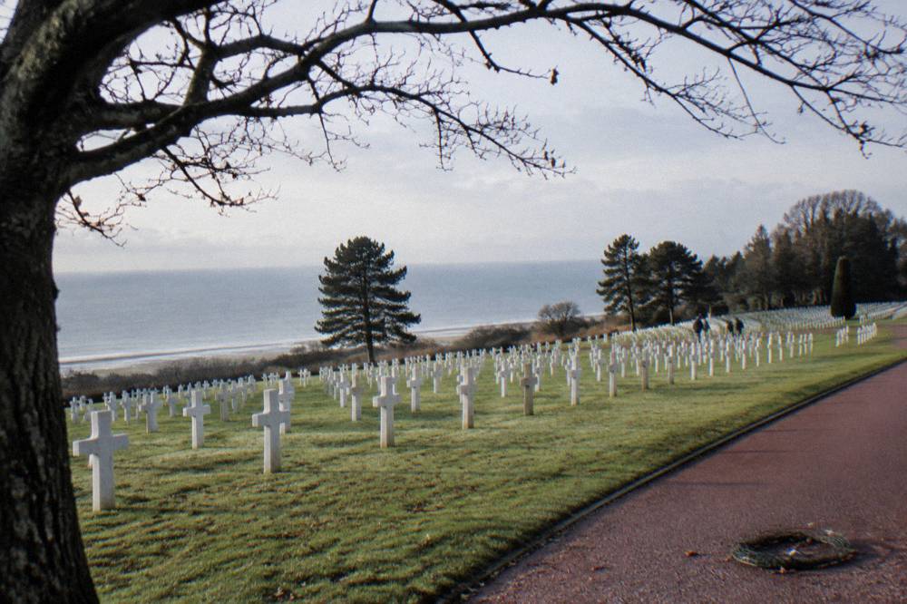 Rows of white headstones in the Normandy American Cemetery below the trees