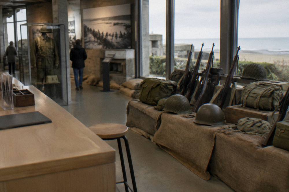 A museum ticket counter and entrance sign beside a display of wartime equipment