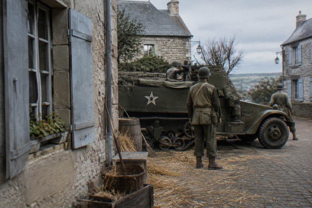 A museum diorama showing soldiers and vehicles staged in a Normandy village scene