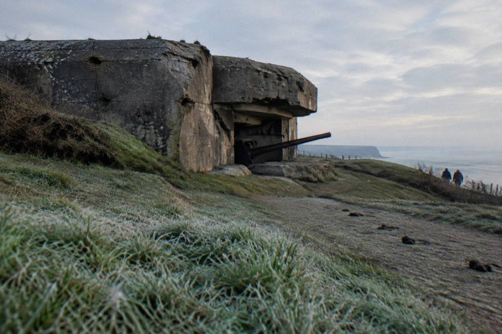 Concrete bunker with shell damage on a clifftop above the sea
