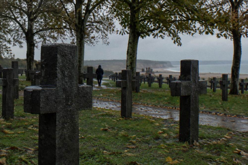 German war cemetery at La Cambe with dark stone crosses among plane trees