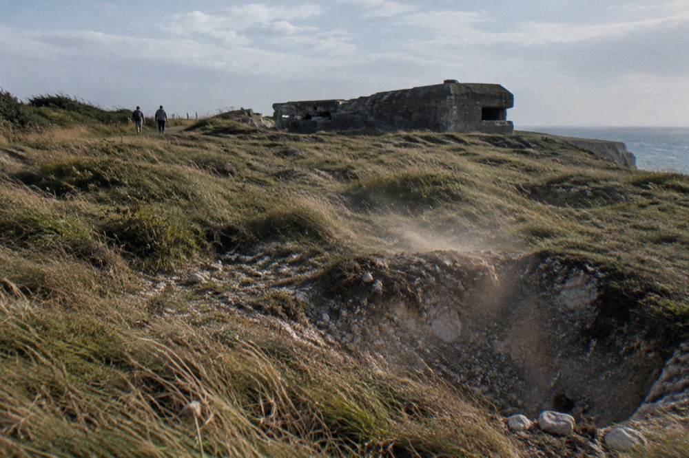Cliff top landscape at Pointe du Hoc with wind-shaped grass and wartime craters