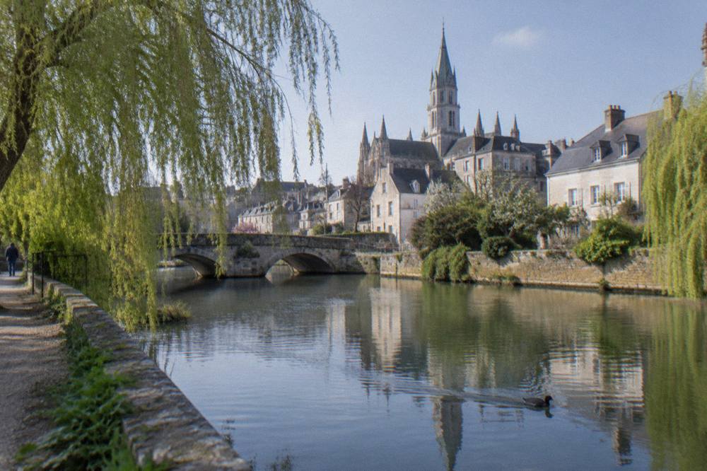 Stone houses and a small bridge over a calm river in Bayeux