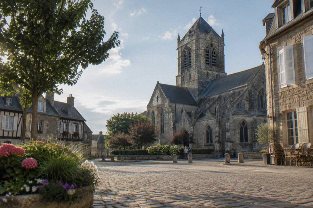 Stone church and main square of a small Normandy market town with timber-framed buildings