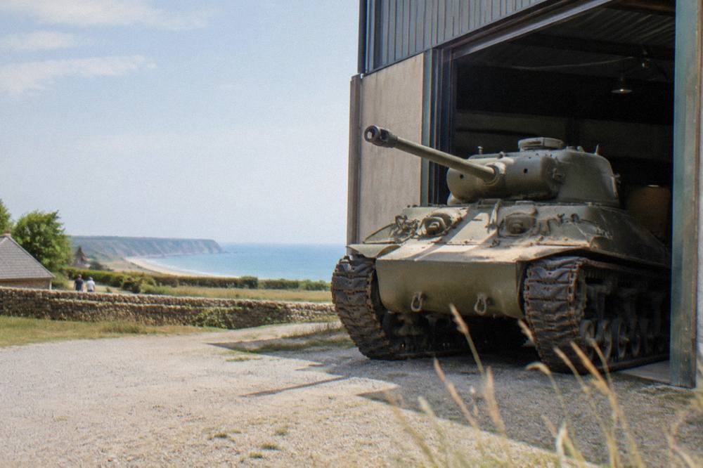 Restored tanks and military vehicles displayed in a museum hangar near the Normandy coast