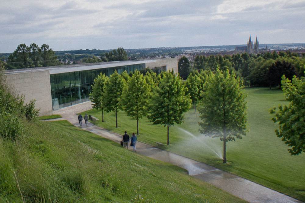 Modern museum building with large glass facade and peaceful parkland