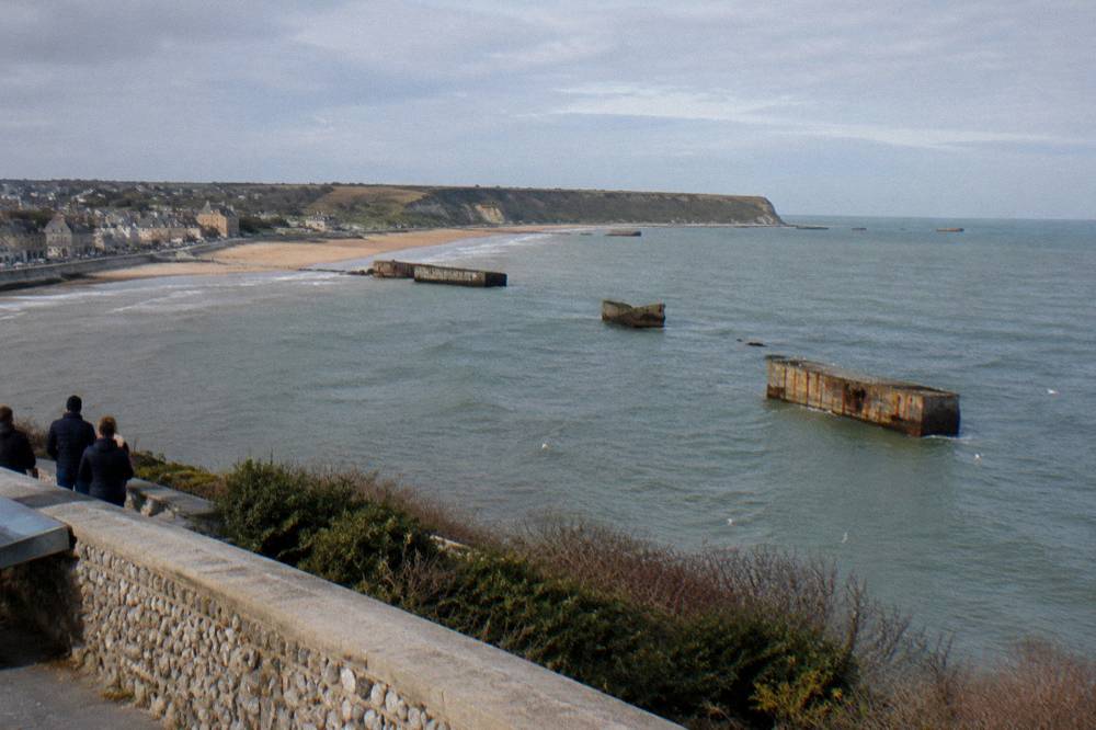 Concrete harbor remains visible in the sea below a cliff-top museum in Arromanches