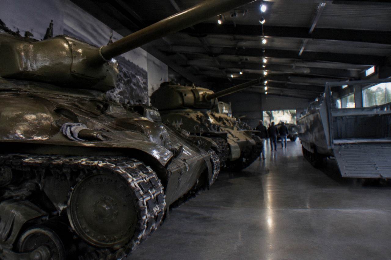 Museum hall with vintage military vehicles and landing craft displays under soft lighting