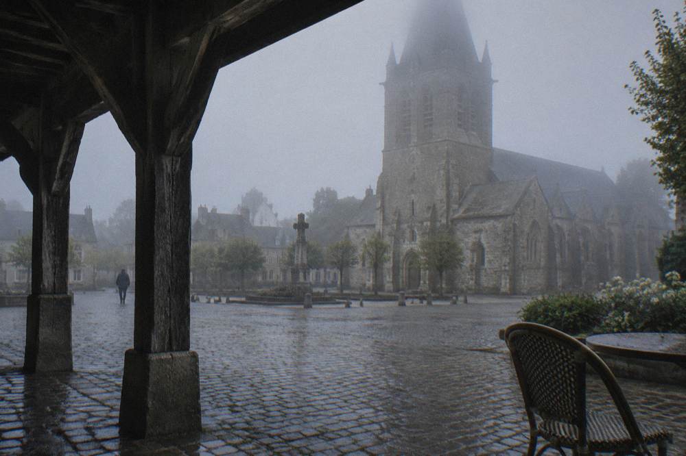 A stone church square in a small Normandy town at morning