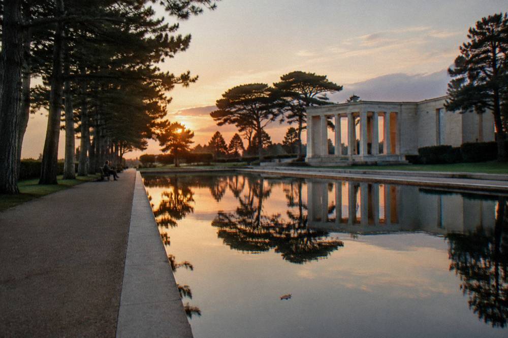 A quiet tree-lined walkway beside a reflecting pool at a memorial site