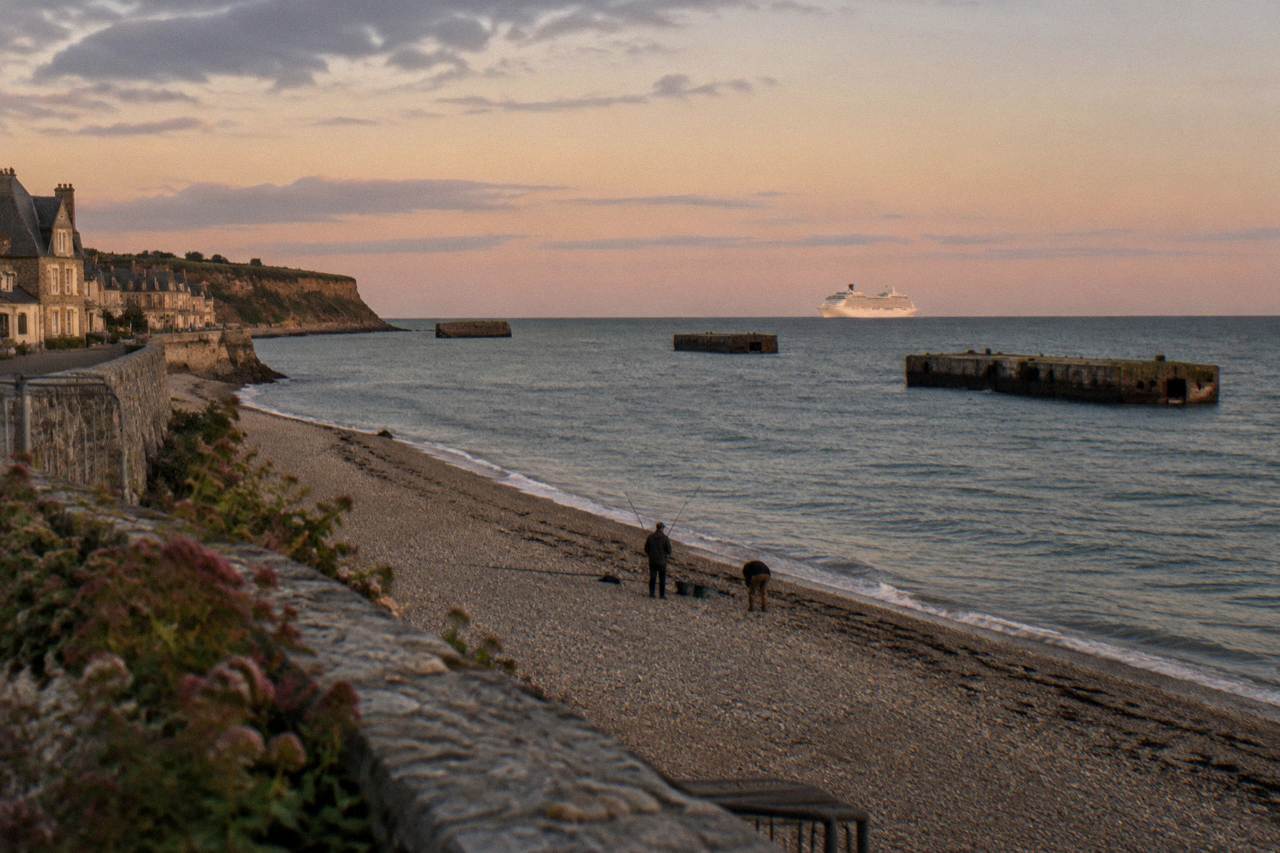 Cruise ship at a Normandy port with green coastline behind it