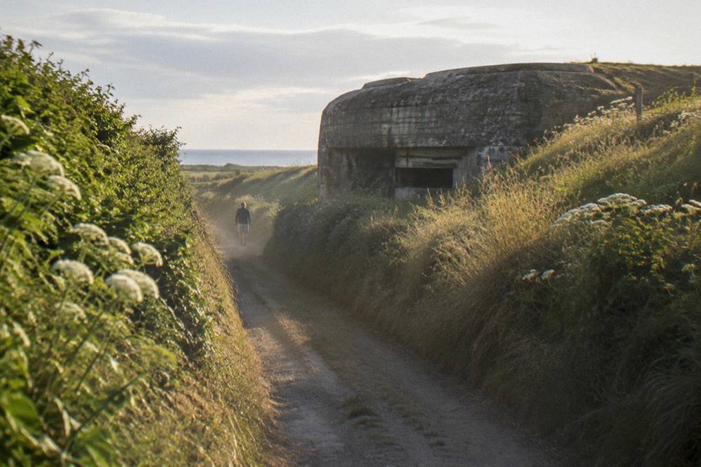 Tour coach parked on a rural lane near the Normandy coastline with hedgerows on both sides