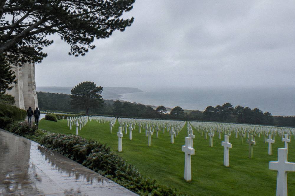 Row of white crosses in the Normandy American Cemetery above the tree line
