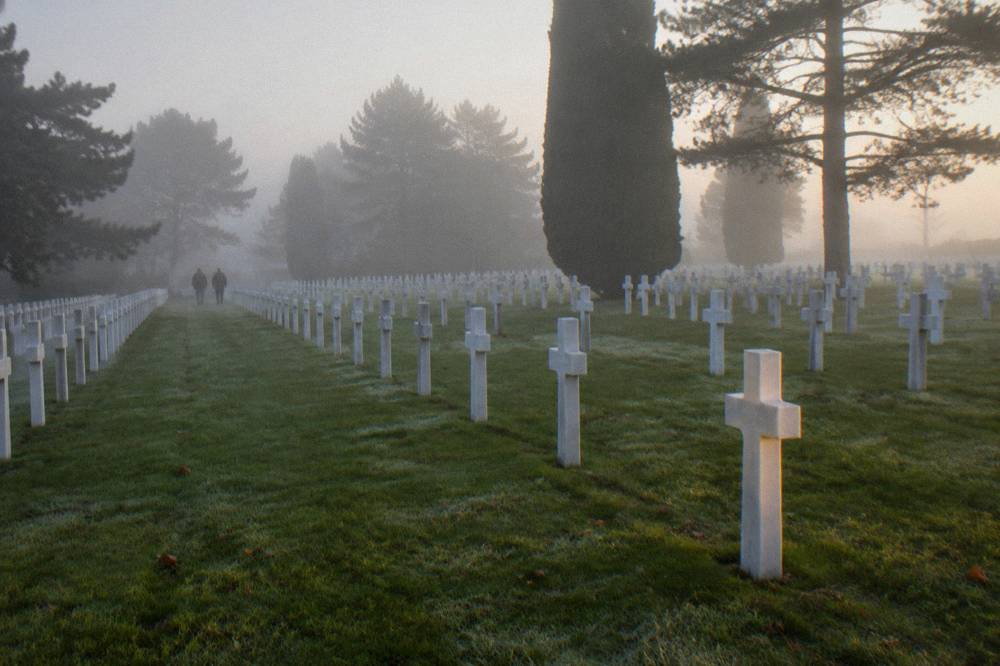 Rows of white marble crosses in a tree-lined military cemetery