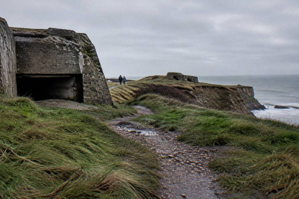 Rough grass path along the cliff edge at Pointe du Hoc under a gray sky