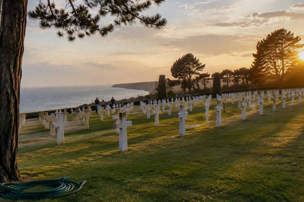 Rows of white markers aligned above the green lawn of the American Cemetery