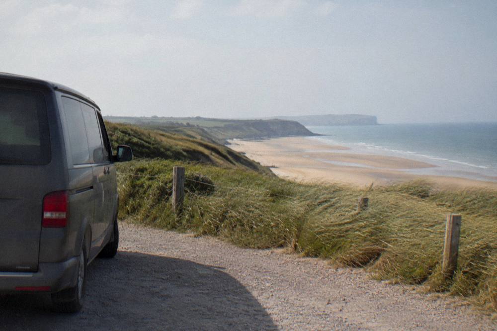 A parked van beside the dunes at the edge of a Normandy landing beach