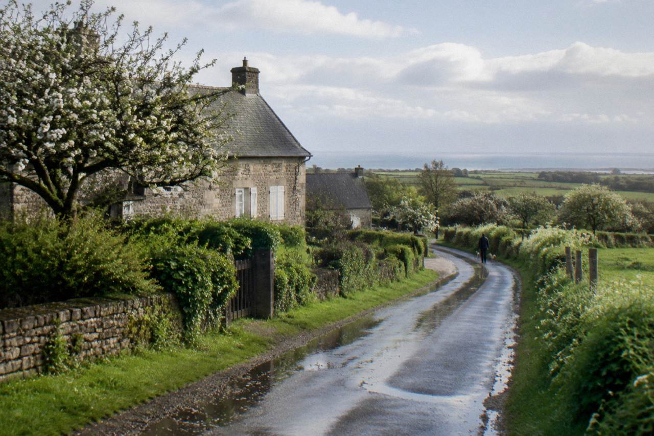 A quiet country road through Normandy farmland leading toward the D-Day landing beaches