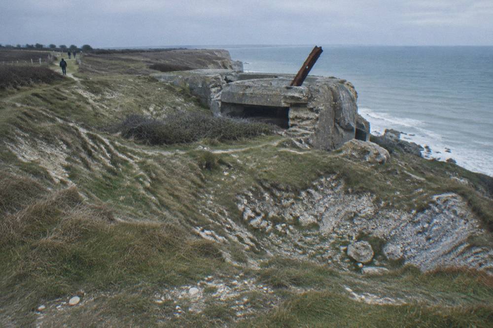 Clifftop landscape at Pointe du Hoc with wind-swept grass and concrete bunker remains