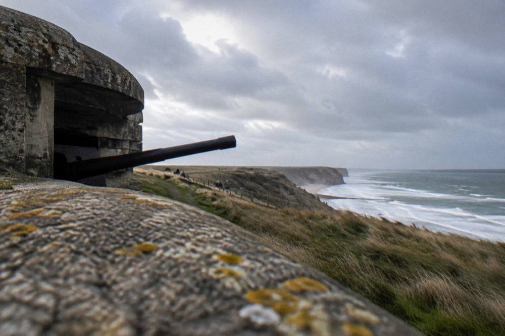 A weathered concrete German bunker on dune grass above a wide empty beach